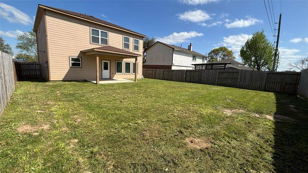 Spacious, fenced backyard featuring a covered patio.