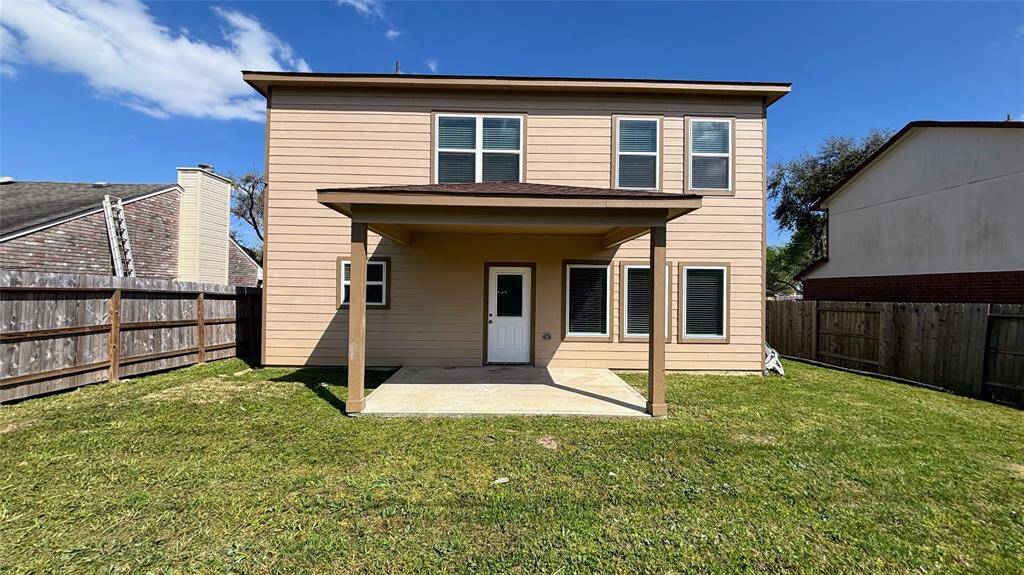 Spacious, fenced backyard featuring a covered patio.