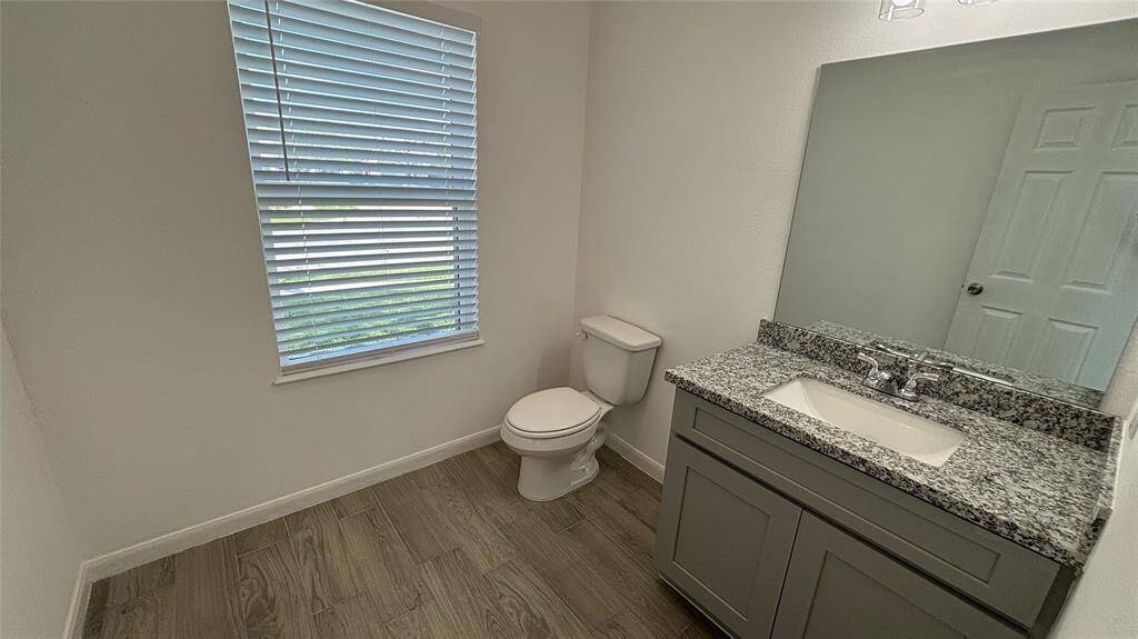 The half  bathroom on the first floor features a modern design with a granite countertop.