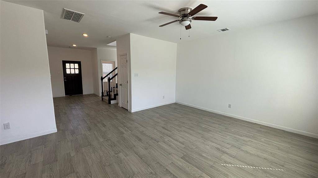 Bright, open living room with light tile flooring and neutral walls. It features a ceiling fan, recessed lighting.