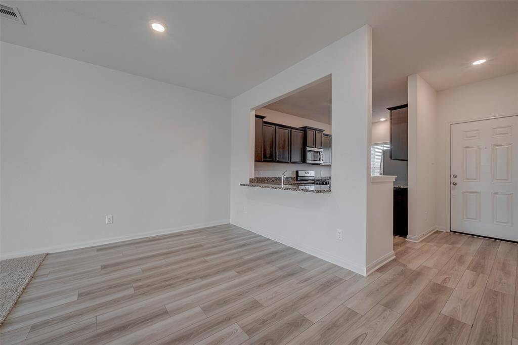 Wood look laminate flooring runs throughout the entryway, kitchen, and dining area.