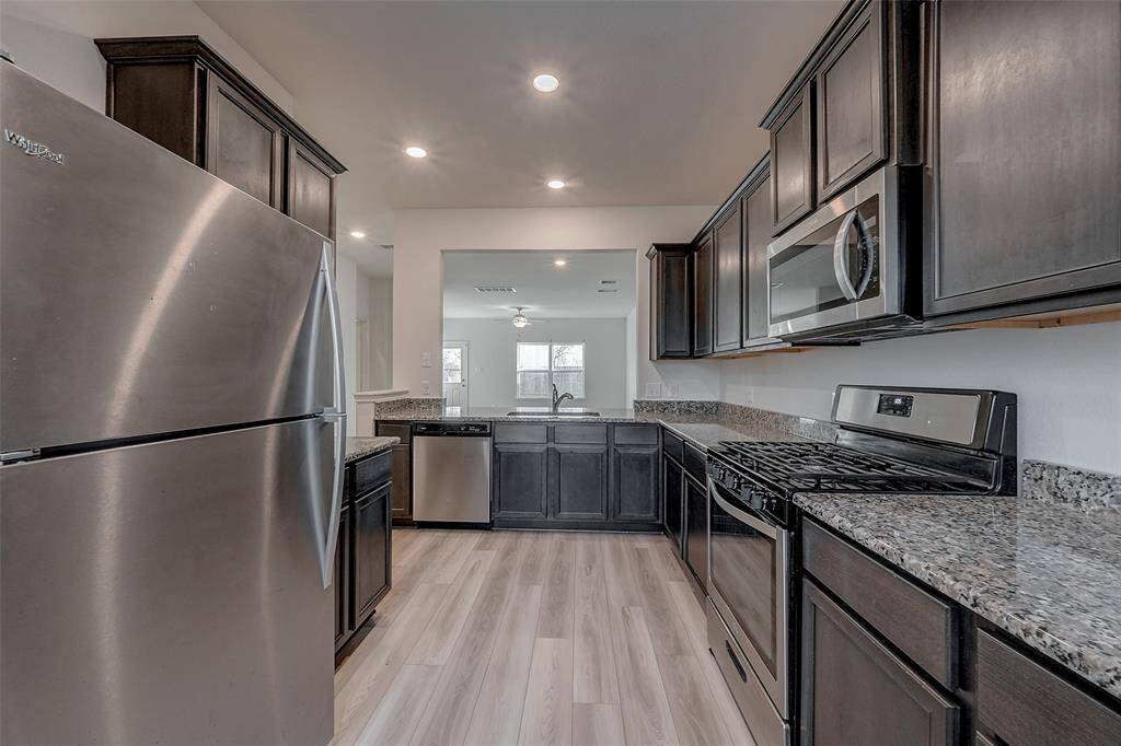 The kitchen is equipped with the stainless steel appliances including the refrigerator.