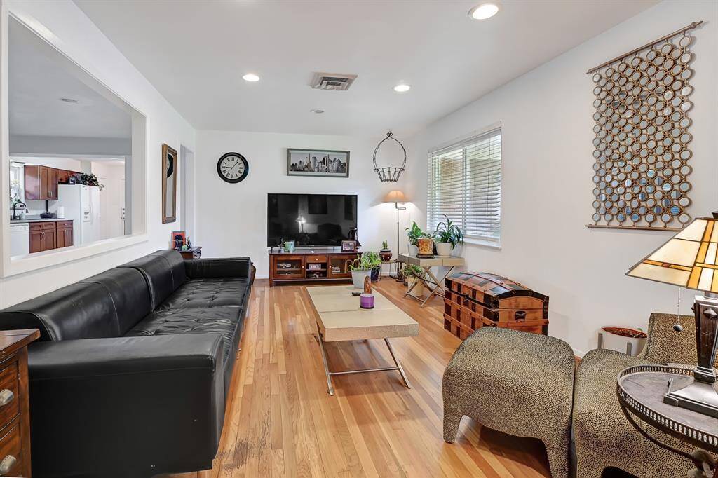 Ample natural light streams in through the window. The adjacent kitchen is visible through a pass-through, enhancing the open feel.