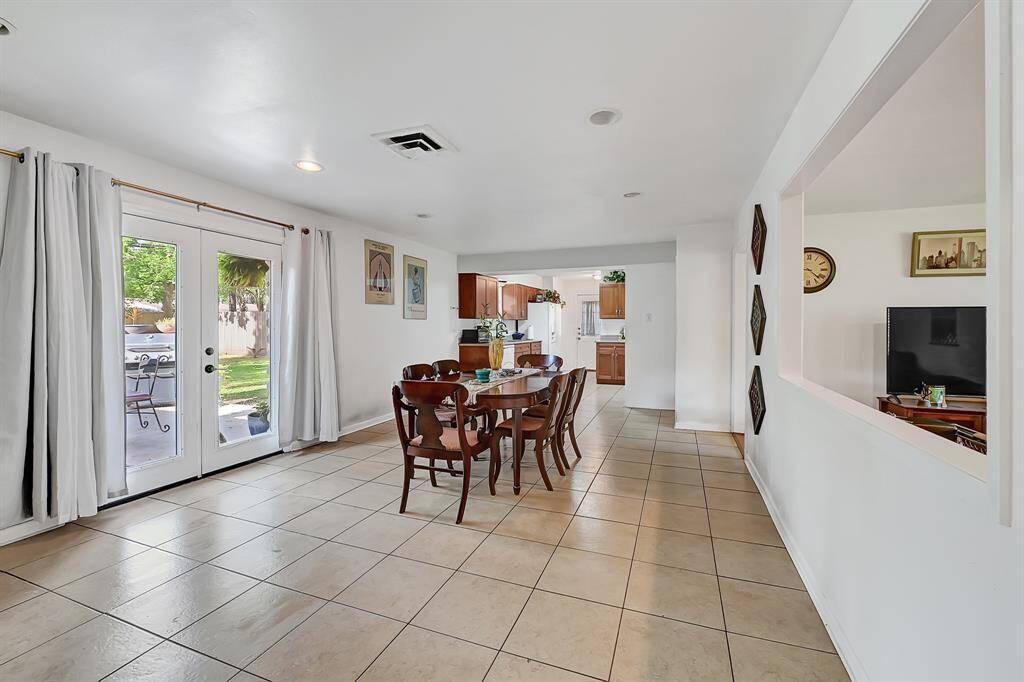 This spacious dining area features tile flooring and ample natural light from large glass doors leading to the backyard. Adjacent to the kitchen, it offers a cozy, open layout perfect for gatherings.