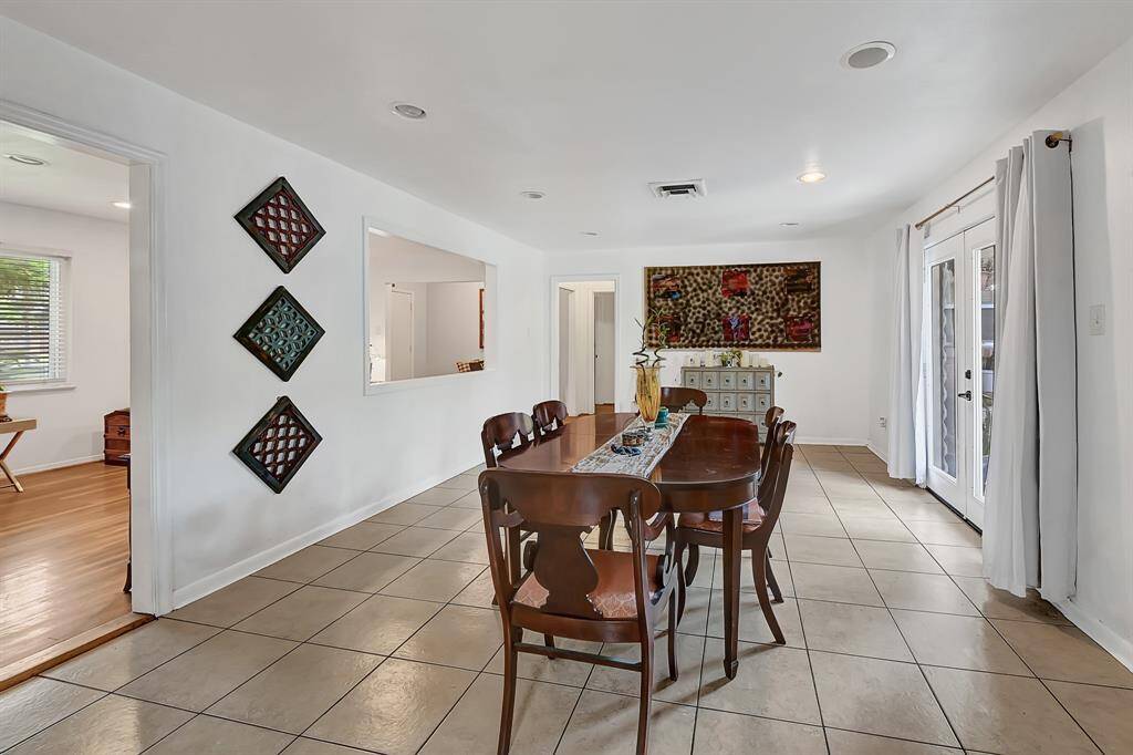 This spacious dining area features tile flooring and ample natural light from large glass doors leading to the backyard. Adjacent to the kitchen, it offers a cozy, open layout perfect for gatherings.