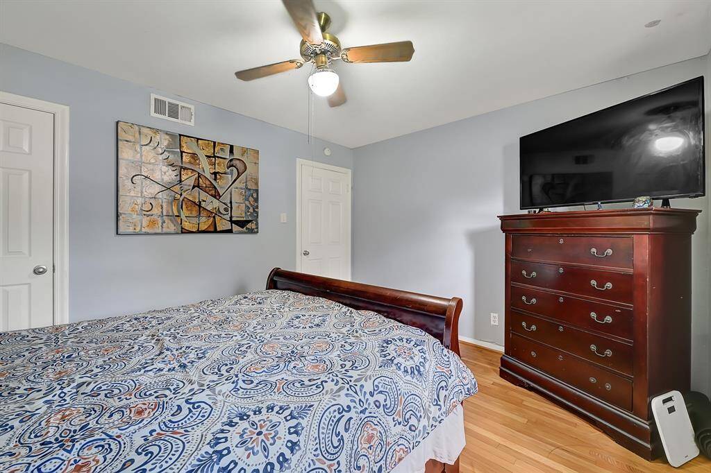 This bedroom features light blue walls, a ceiling fan, and hardwood flooring.