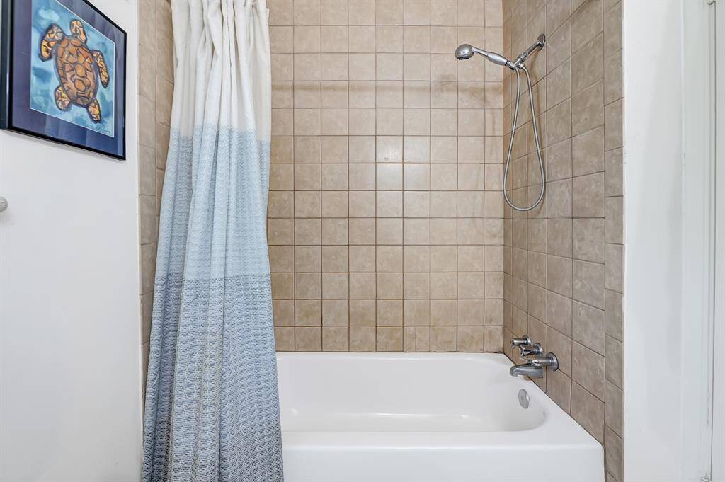 This bathroom features a tiled shower and tub combo with a modern showerhead.