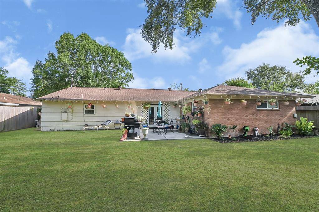 Charming backyard with a spacious lawn, patio area for entertaining, and well-maintained garden beds.
