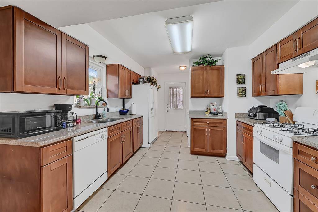 This kitchen features warm wood cabinets, tiled flooring, and ample counter space.