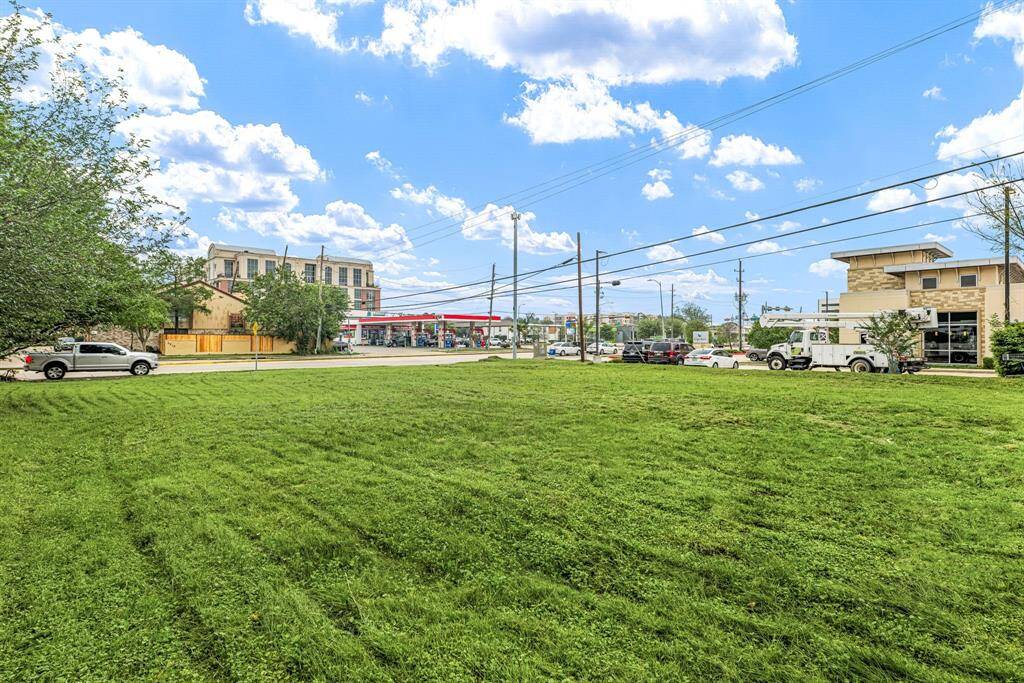 Spacious grassy lot in an urban setting with nearby commercial buildings and a gas station. Ideal for development or investment, offering convenient city access.