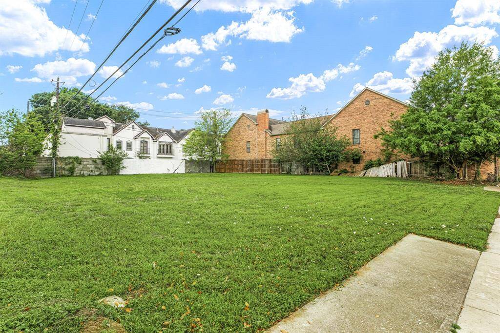 Expansive grassy lot with a clear view of neighboring homes, featuring a mix of brick and stucco exteriors. Ideal for new construction or landscaping opportunities.