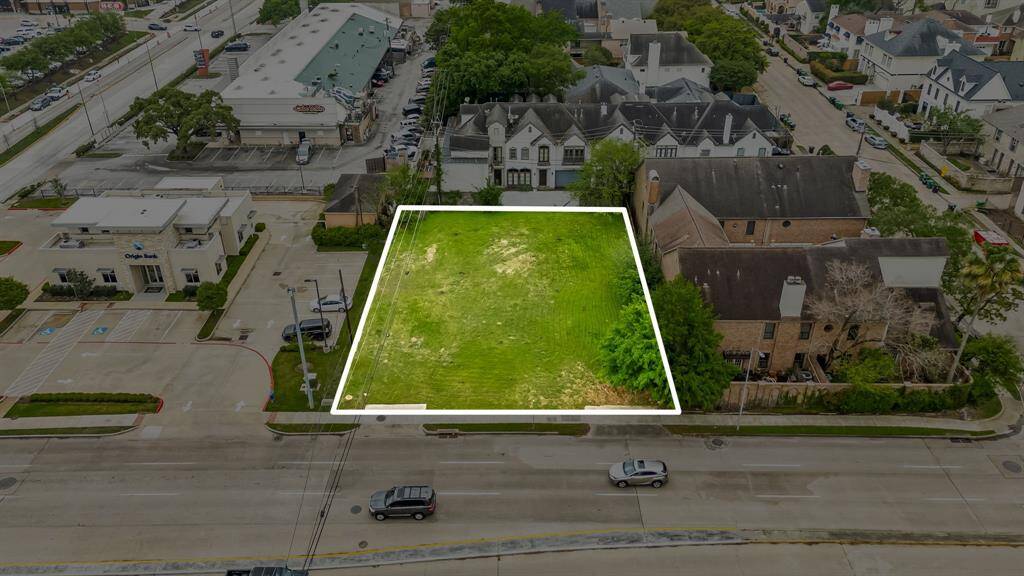 This photo shows a vacant plot of land in a suburban area, outlined for emphasis. It's surrounded by commercial buildings, residential houses, and has street access. Ideal for development, the lot offers a blend of urban convenience and residential charm.