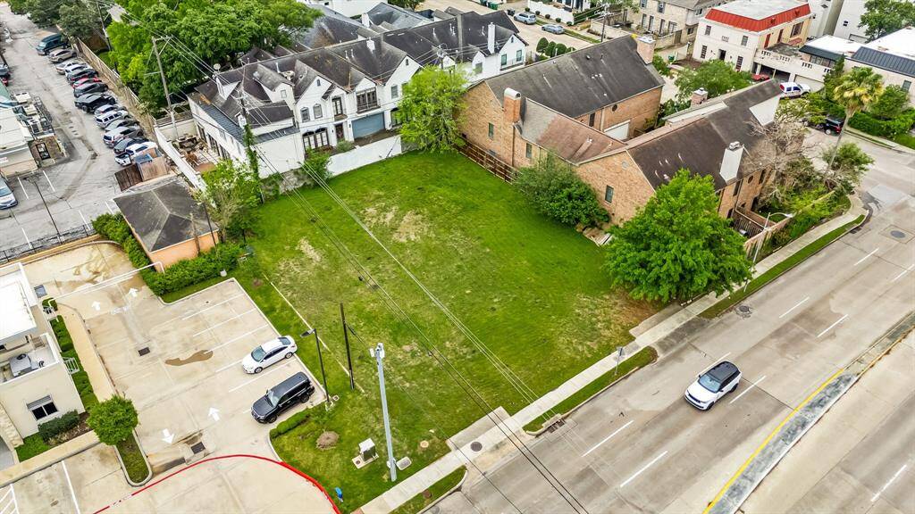Spacious vacant lot in an urban setting, surrounded by residential and commercial buildings. The area is well-maintained, with ample parking space nearby and easy street access. Ideal for new construction or investment.