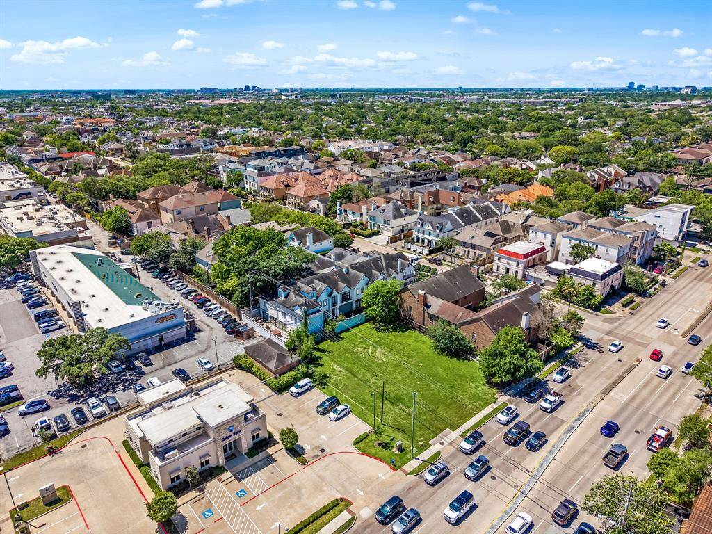 This aerial photo showcases a vibrant neighborhood with a mix of residential homes and commercial buildings. It features tree-lined streets, ample parking, and proximity to shops, providing a blend of community and convenience.