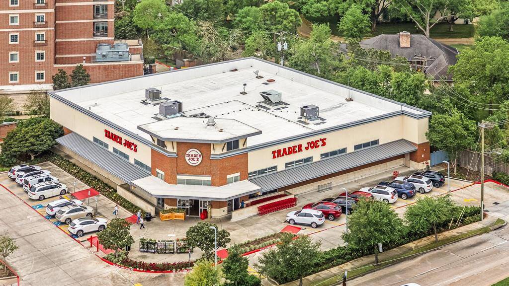 This photo shows a Trader Joe's store with a spacious parking lot, nestled in a green, tree-lined area. It's conveniently located near residential buildings, ideal for easy grocery access.