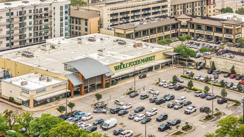 This photo shows a bustling urban area featuring a large grocery store with ample parking. There are residential and commercial buildings nearby, providing convenient access to shopping and amenities.