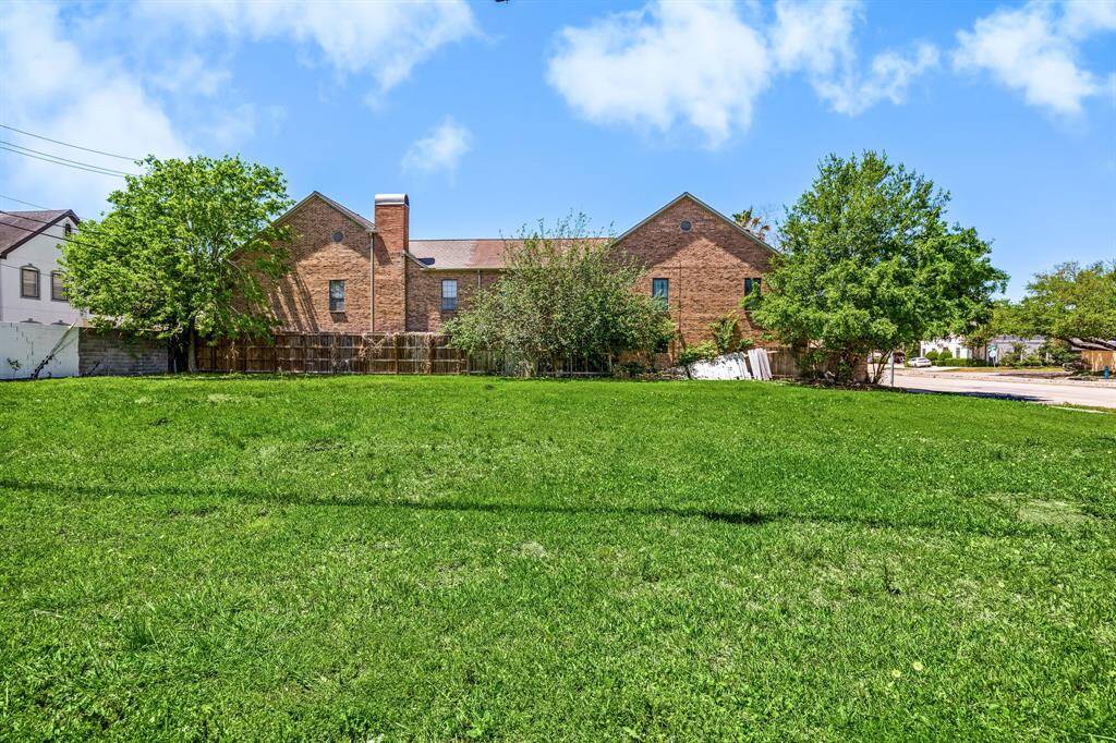 Spacious grassy lot in an urban setting with nearby commercial buildings and a gas station. Ideal for development or investment, offering convenient city access.