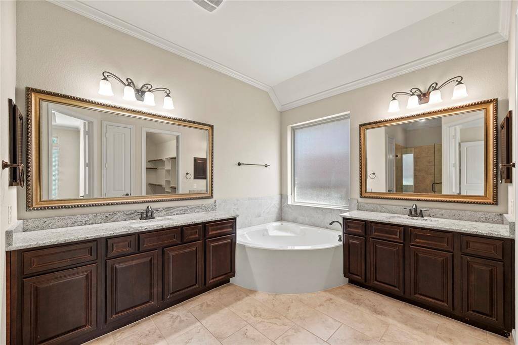 The primary bath features exquisite dual vanities, providing ample personal space along with an abundance of custom cabinetry for seamless organization.