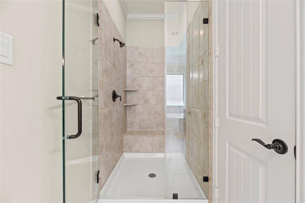 The expansive walk-in shower, with stunning tile work and a sleek glass front, offers a perfect escape for a quick rinse or a refreshing retreat.