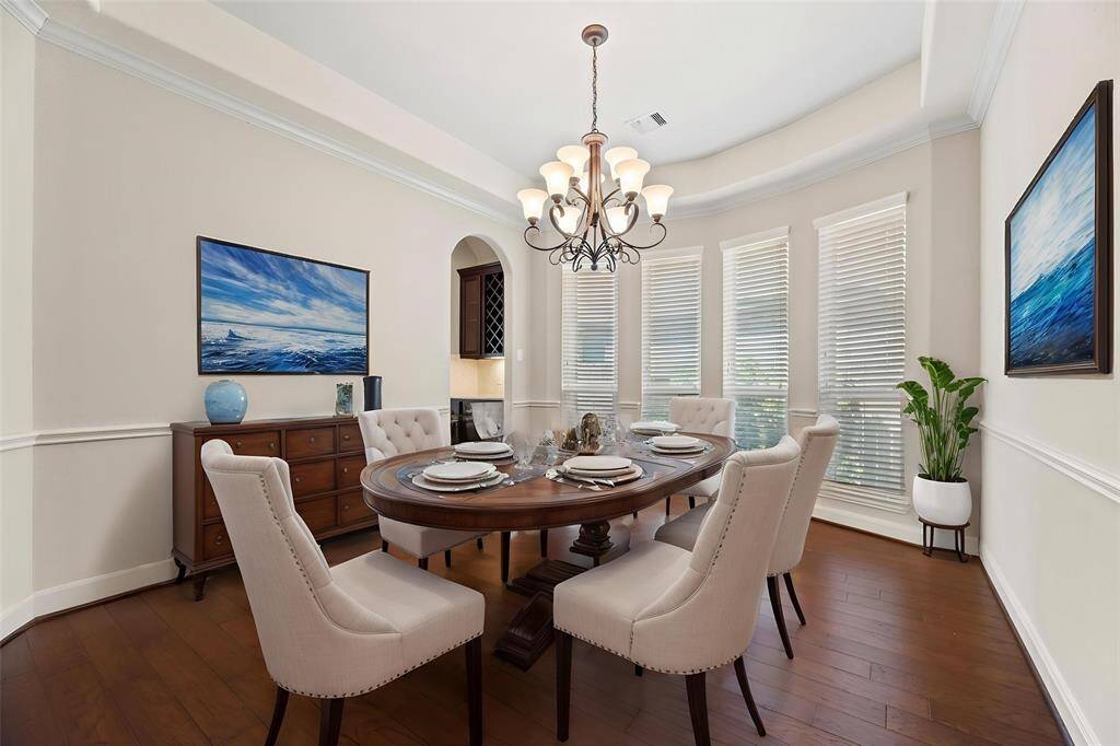 This spacious dining room is perfect for entertaining and will accommodate those extended family, special meals. The combination of beautiful ceiling lines and wood flooring sets a stunning backdrop for the formal dining space, adding warmth, texture, and architectural interest. - virtually staged