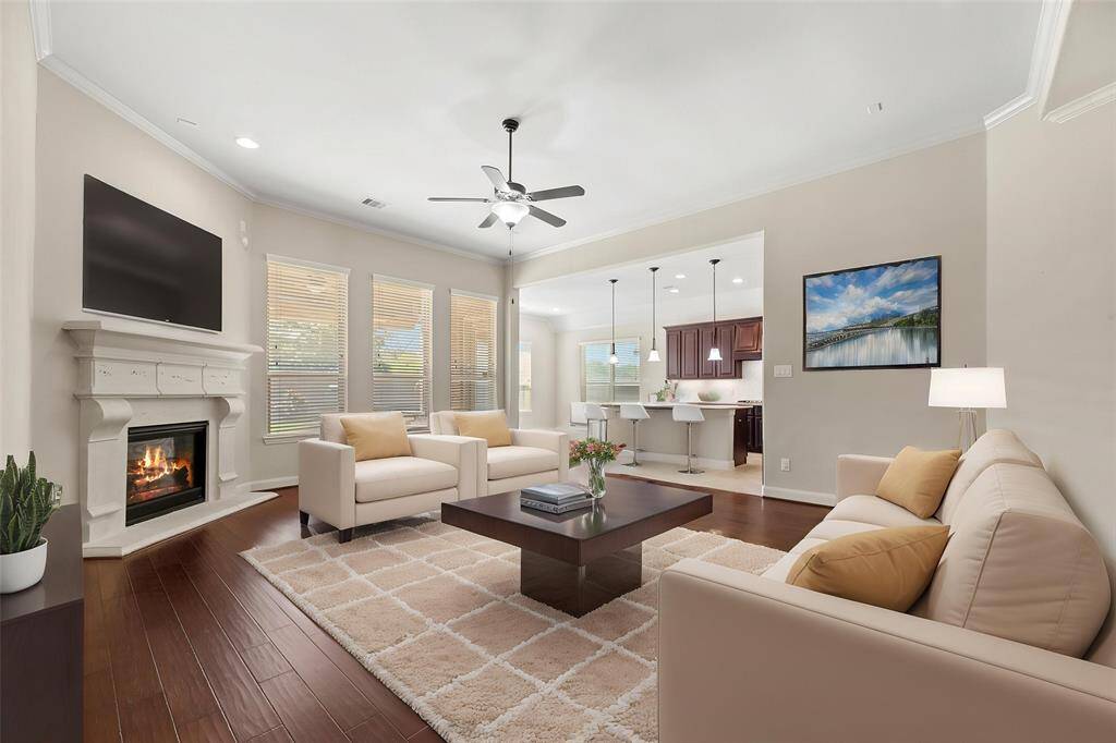 This chic living room space has a great feel with tons of natural light coming from the wall of windows. 56.The family room features hardwood floors, modern light fixture, recessed lighting, tall ceilings, and a corner fireplace. - virtually staged