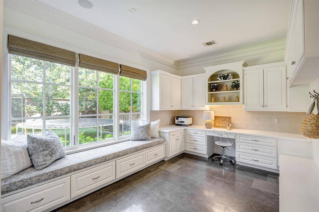 The home office/study off the kitchen has a built-in desk and seating, complemented by extra cabinets and drawers for ample storage.