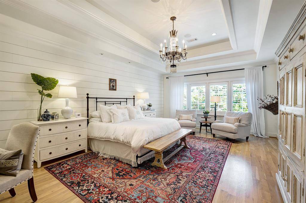 Spacious primary bedroom features shiplap walls, detailed millwork, and rich hardwood floors.