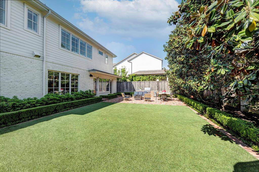 The expansive backyard features lush landscaping and artificial turf lawn.