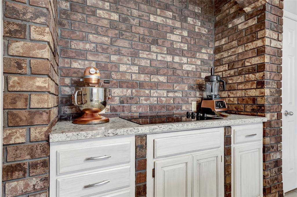 Built-in cooktop surrounded by a beautiful brick accent wall with tons of storage