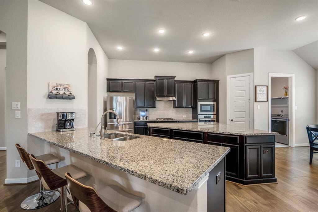 The heart of the home! This stunning chef’s kitchen features elegant wood cabinetry, a spacious island and peninsula with seating, built-in stainless steel appliances, and recessed lighting—perfect for gathering and entertaining.