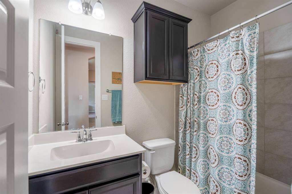 This full bathroom is located just down the hallway of the first secondary bedroom and is the perfect place for guests to get ready in while visiting. It features beautiful countertops, wood cabinets, large mirror, and a spacious combination tub and shower.