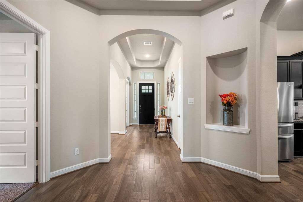 The grand foyer includes a beautiful rotunda making the home feel warm and inviting. It features high ceilings, neutral paint, and decorative art niches.
