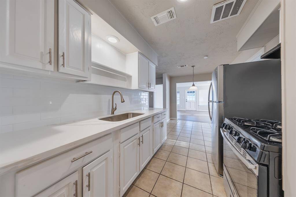 This inviting kitchen features sleek quartz countertops, a stainless steel fridge, and a gas stove, combining style and functionality. With abundant cabinetry and ample lighting, it opens seamlessly to the dining and living areas, making it perfect for both cooking and entertaining.