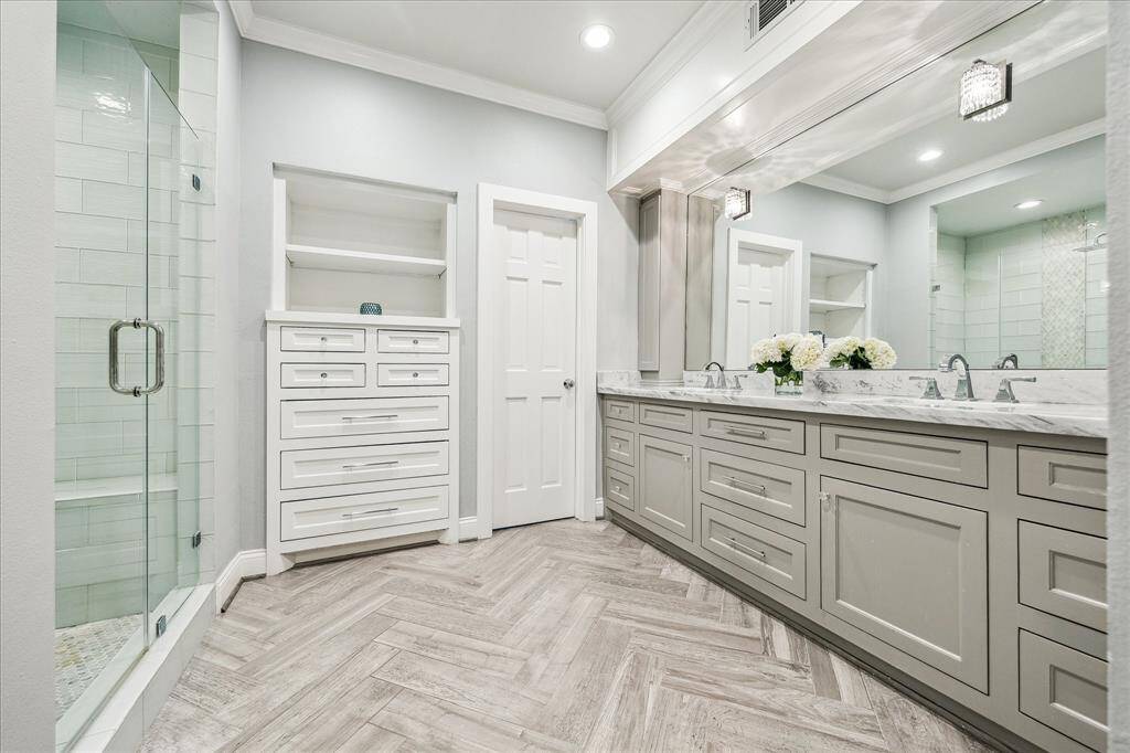 The primary bedroom on the first level features a beautifully renovated en-suite bath, complete with custom soft-close cabinetry, marble countertops, and a sleek glass shower. Every detail has been thoughtfully designed. Two walk-in closets are not shown.