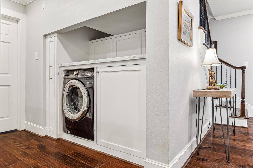 The washer and dryer area is equipped with a custom pull-out door for additional storage, offering a practical and organized solution for laundry needs. This is one of two laundry areas, as there is another in the garage.