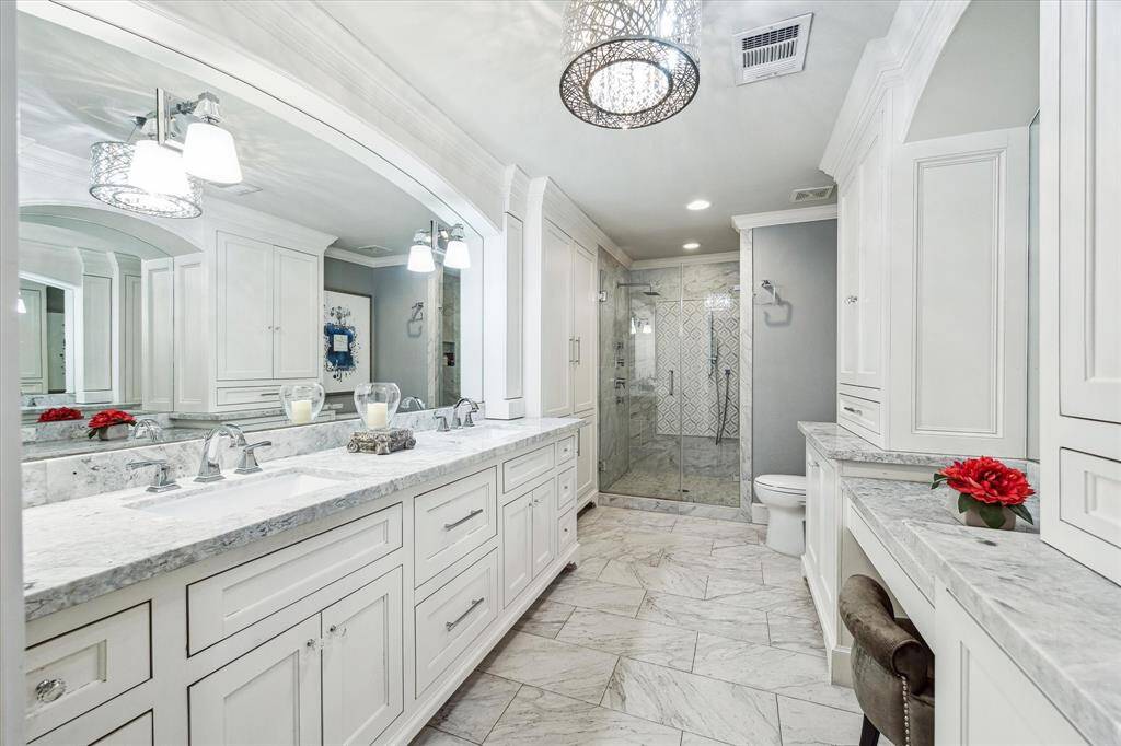 This large bathroom, shared by the game room and secondary bedroom, has been beautifully renovated. It features dual sinks, custom inset cabinetry, stunning marble, and a gorgeous shower, providing both style and functionality for the space.