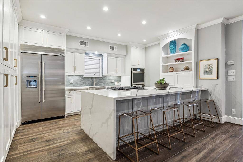 The gourmet kitchen is a culinary masterpiece, featuring spacious sleek quartz countertops with a waterfall edge and built-in seating, perfect for casual dining or gathering. It is equipped with top-of-the-line JennAir appliances.