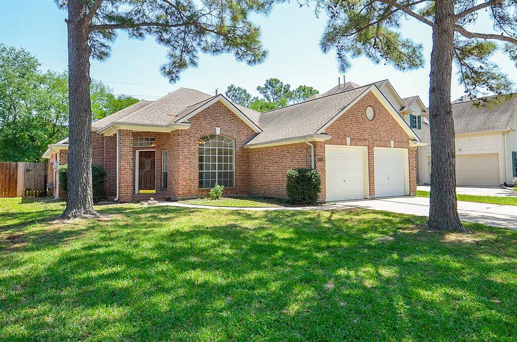 This charming brick home features a welcoming front entrance, large arched window, and a spacious two-car garage. Surrounded by mature trees and a well-maintained lawn