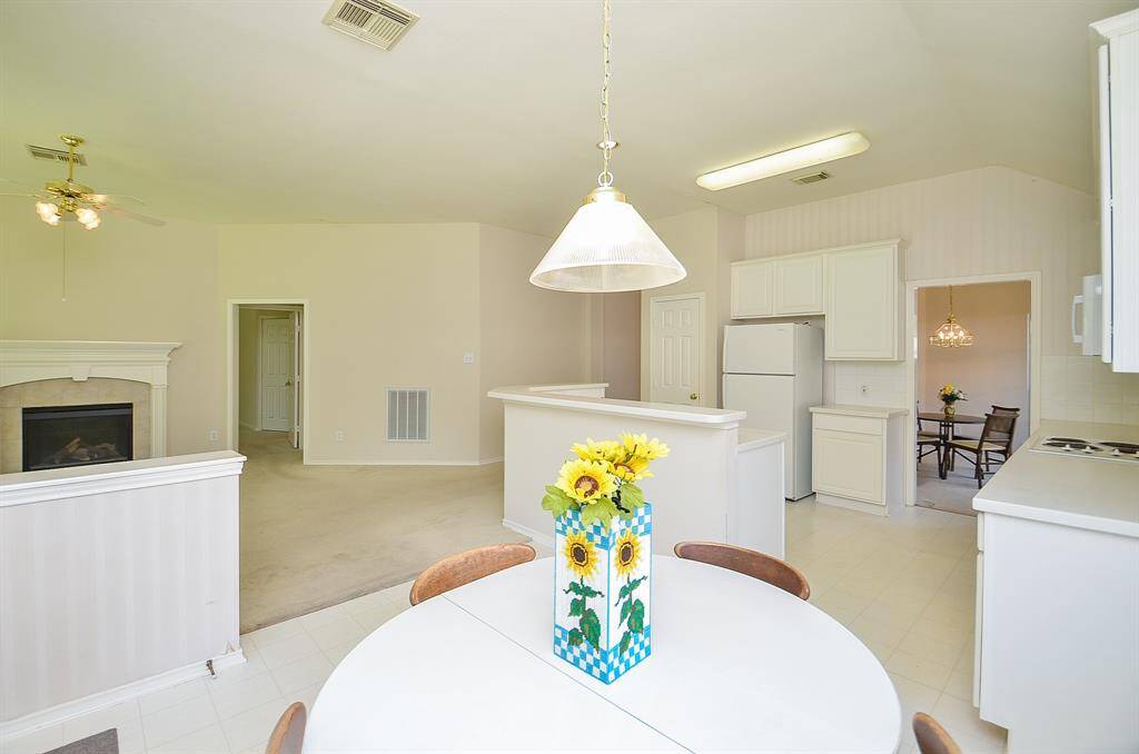 Bright and airy open-plan kitchen and living area with neutral tones. Features a cozy fireplace, dining space, and ample cabinetry. Perfect for entertaining and family gatherings.