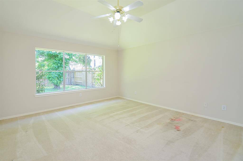 Bright bedroom with large window offering garden views, featuring high ceilings with a ceiling fan.