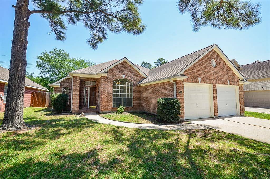 This charming brick home features a welcoming front porch, two-car garage, and well-maintained landscaping. It's nestled among mature trees, offering a cozy feel.