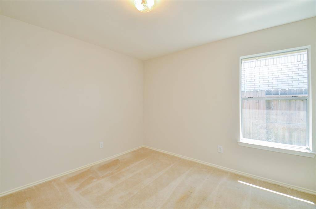 This bedroom offers neutral walls and a large window letting in natural light
