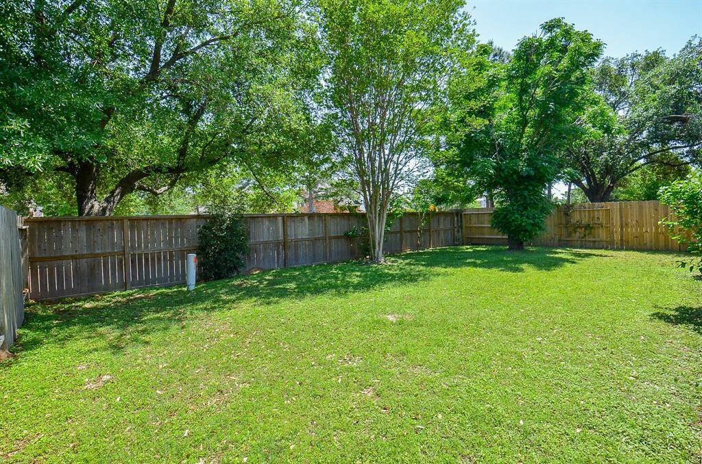 This spacious backyard with mature trees and a wooden fence, providing a private and serene outdoor space perfect for relaxation or entertaining.