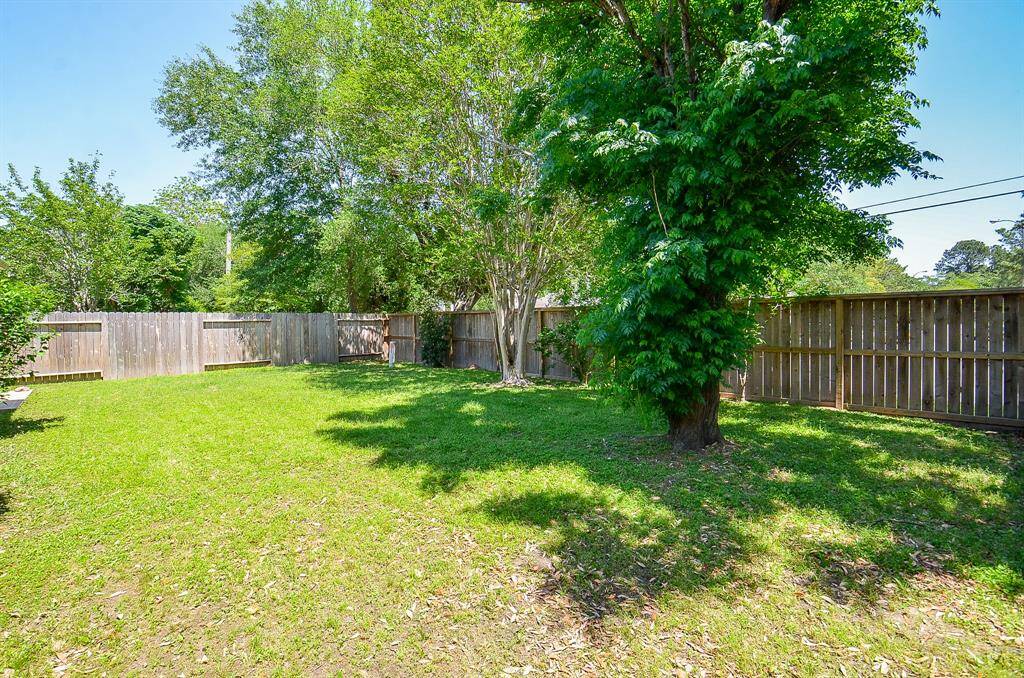 Spacious backyard with lush grass, mature trees, and a wooden privacy fence, perfect for outdoor activities and relaxation.