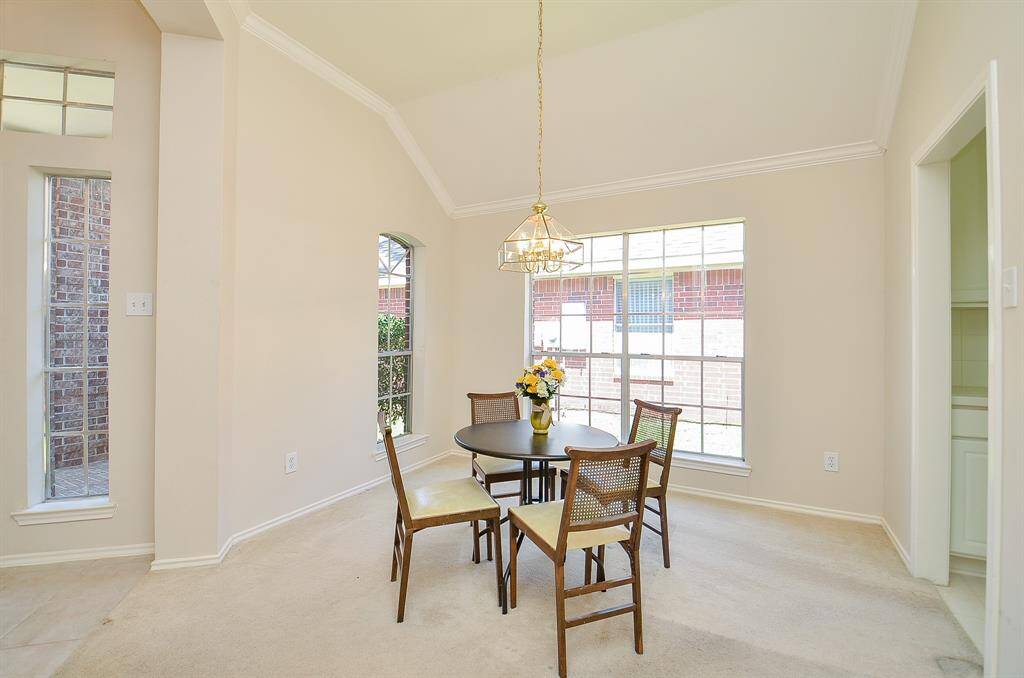 Bright dining area with high ceilings, featuring a large window for natural light.