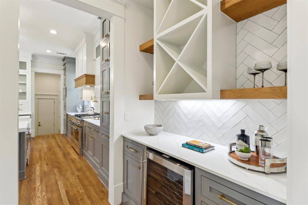 The Butler's pantry features white oak shelving and herringbone Zellige tile, a timeless look and a personal favorite of our design team. Underneath is a wine chiller and storage, and to the left (unpictured) is the walk-in pantry.