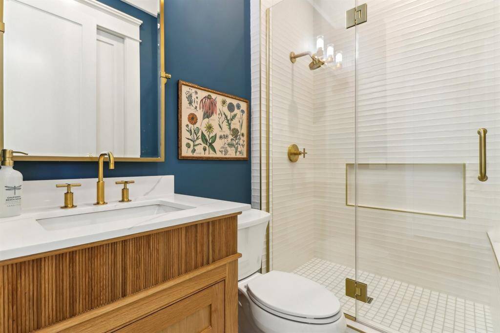 The powder bath is extraordinarily appointed with site-built reeded white oak cabinetry & brass Kohler fixtures.