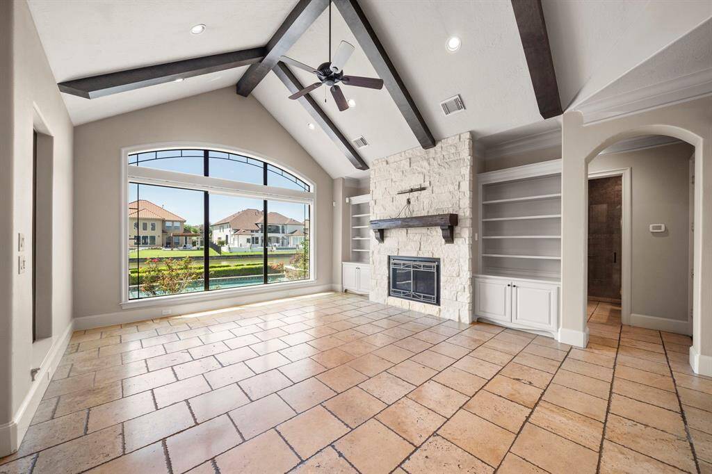 Large open family room with vaulted ceiling, fireplace, built-ins overlooking sparkling pool