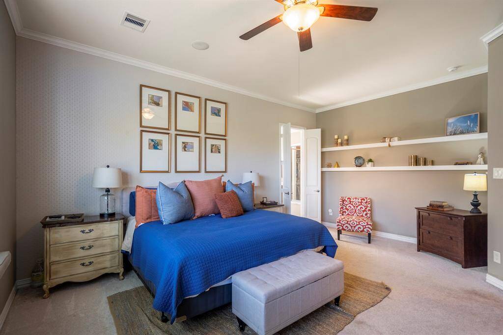 Neutral tones continue through the primary bedroom suite area, with crown molding and shelving.