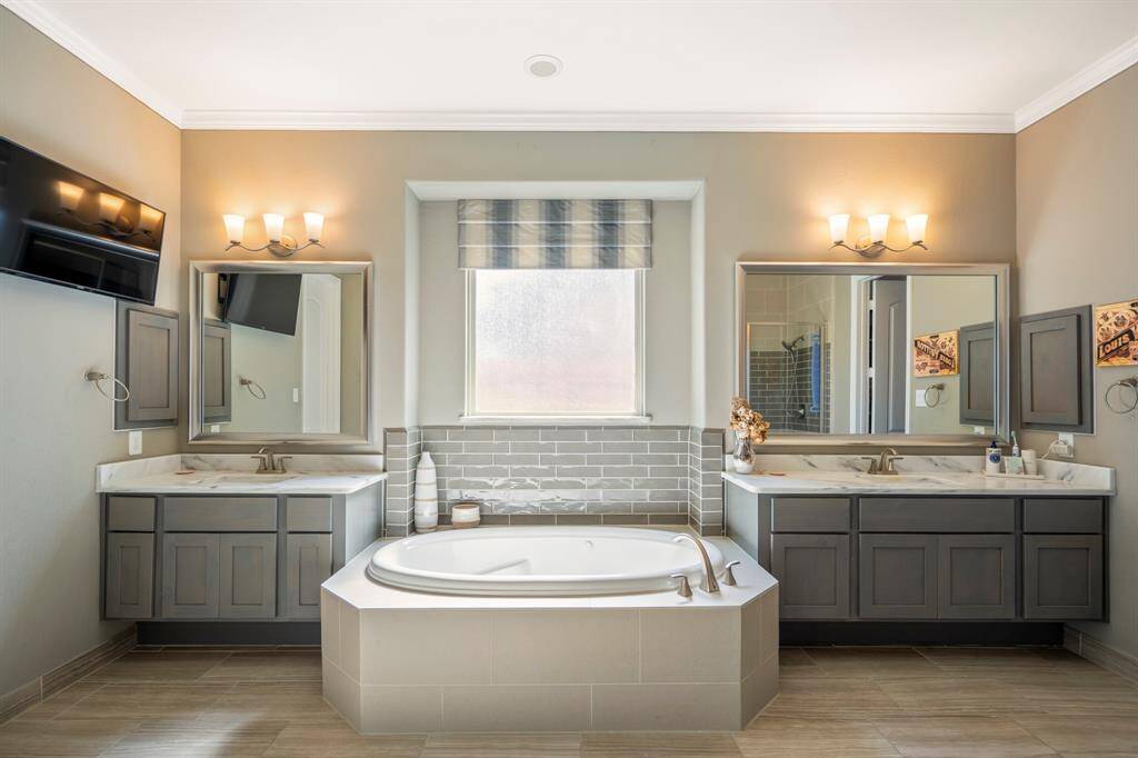 A luxurious soaking tub is central to the en-suite bathroom with dual vanities, uplighting and tiled backsplash offering a nice large window streaming in natural light.
